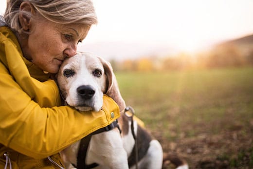 Senior woman with dog on a walk in an autumn nature.